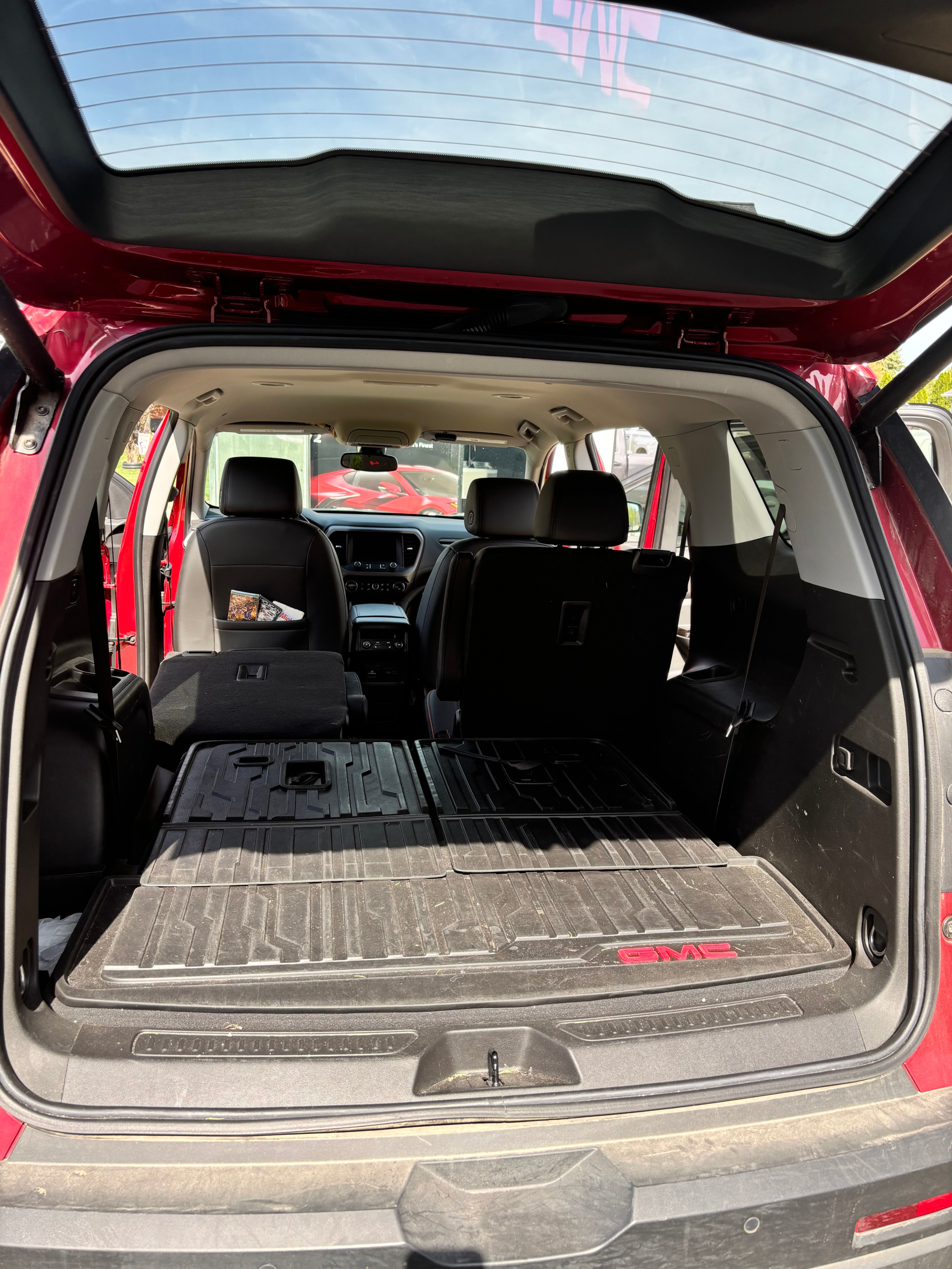 Cargo area of a customer's GMC SUV photographed through the lifted tailgate before interior detailing — wide phone shot showing the cargo floor and rear seats. An example trunk/cargo photo we use to price your interior detail.