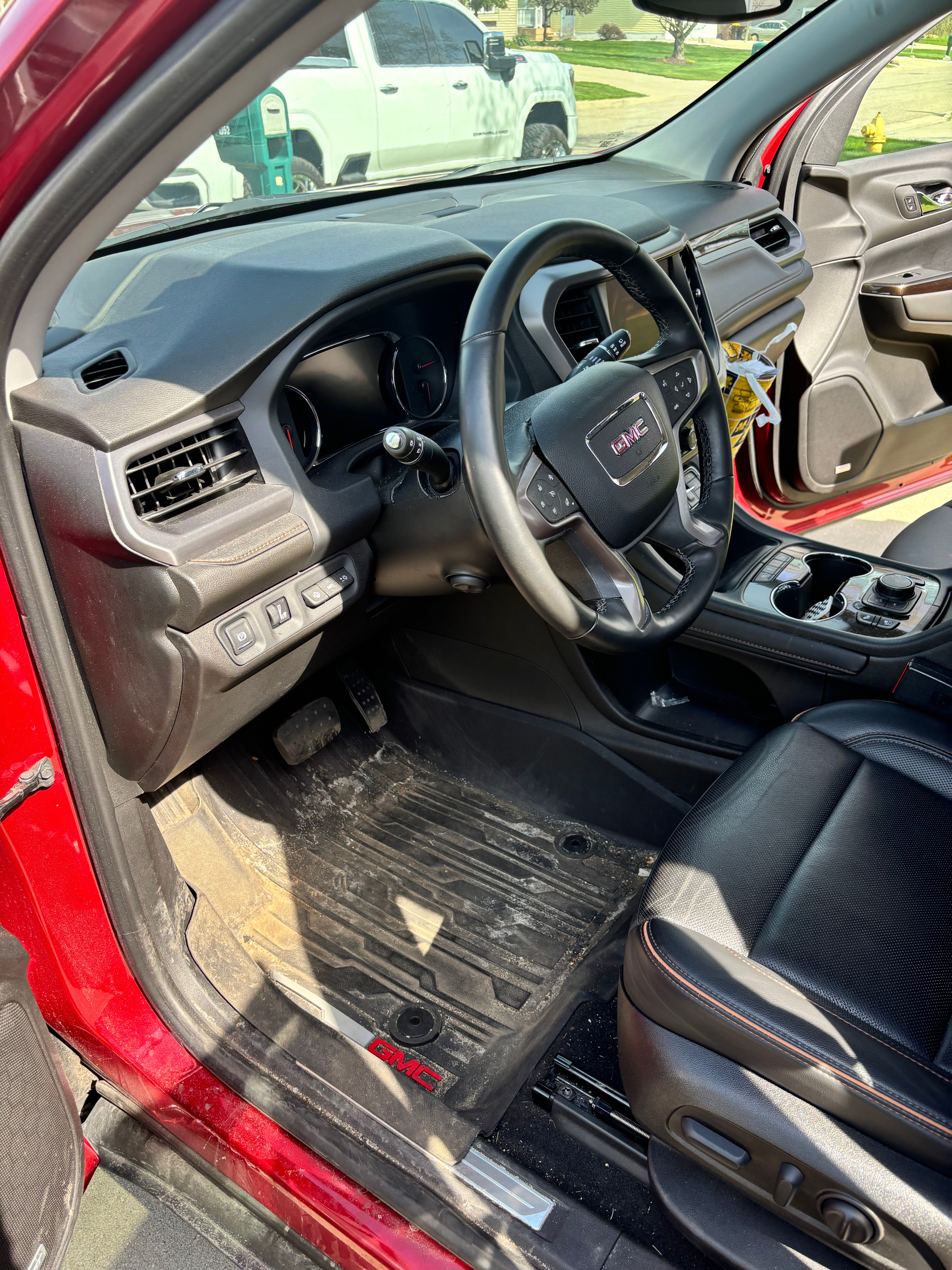 Front seats and driver footwell of a Mid-Michigan customer's GMC SUV photographed before interior detailing — dust on the dash, debris on the floor mat. The kind of phone photo we ask for so we can quote your interior detail accurately.