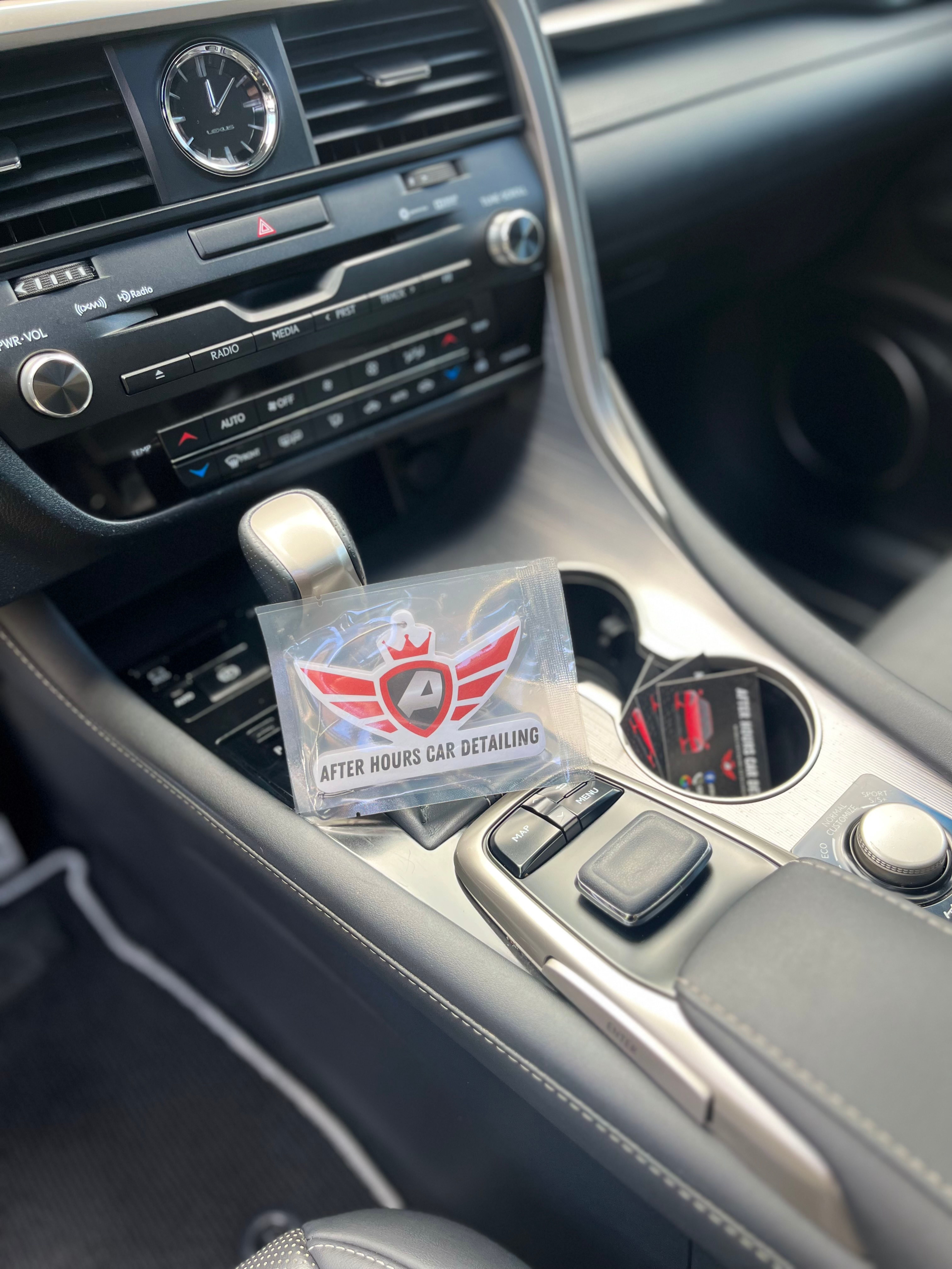 After Hours Car Detailing branded air freshener hanging from the gear shift and AHCD business card placed in the cup holder of a freshly detailed Lexus RX — the calling card we leave so you know the work is done.