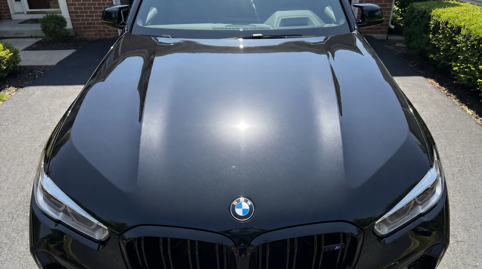 Black BMW X3 M hood paint enhancement polish before and after — swirls removed, gloss deepened — after