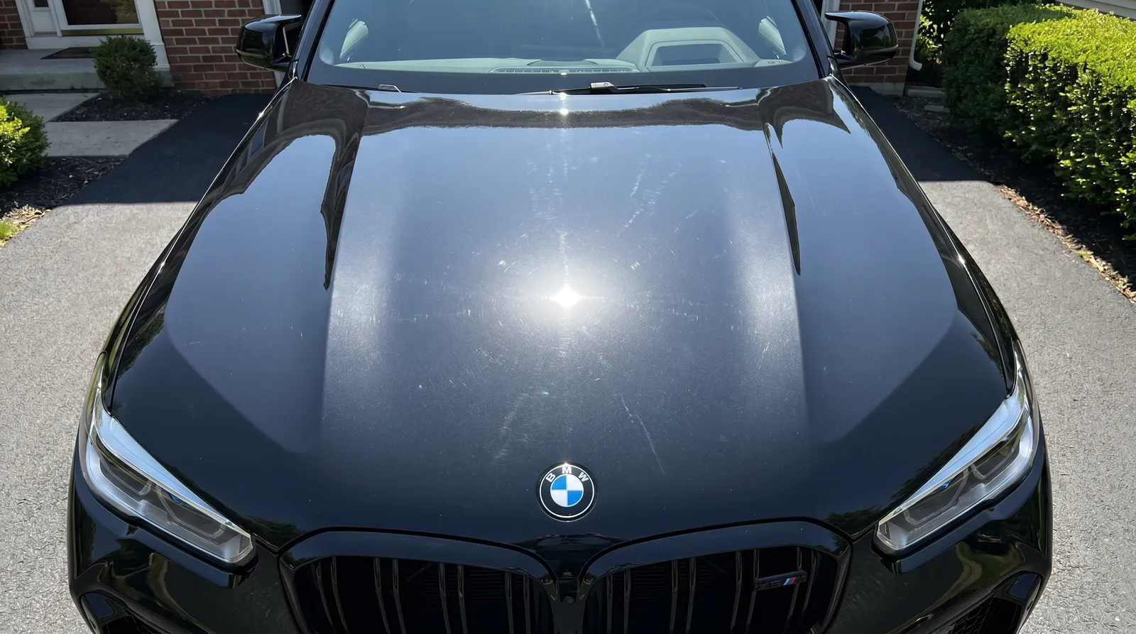 Black BMW X3 M hood paint enhancement polish before and after — swirls removed, gloss deepened — before