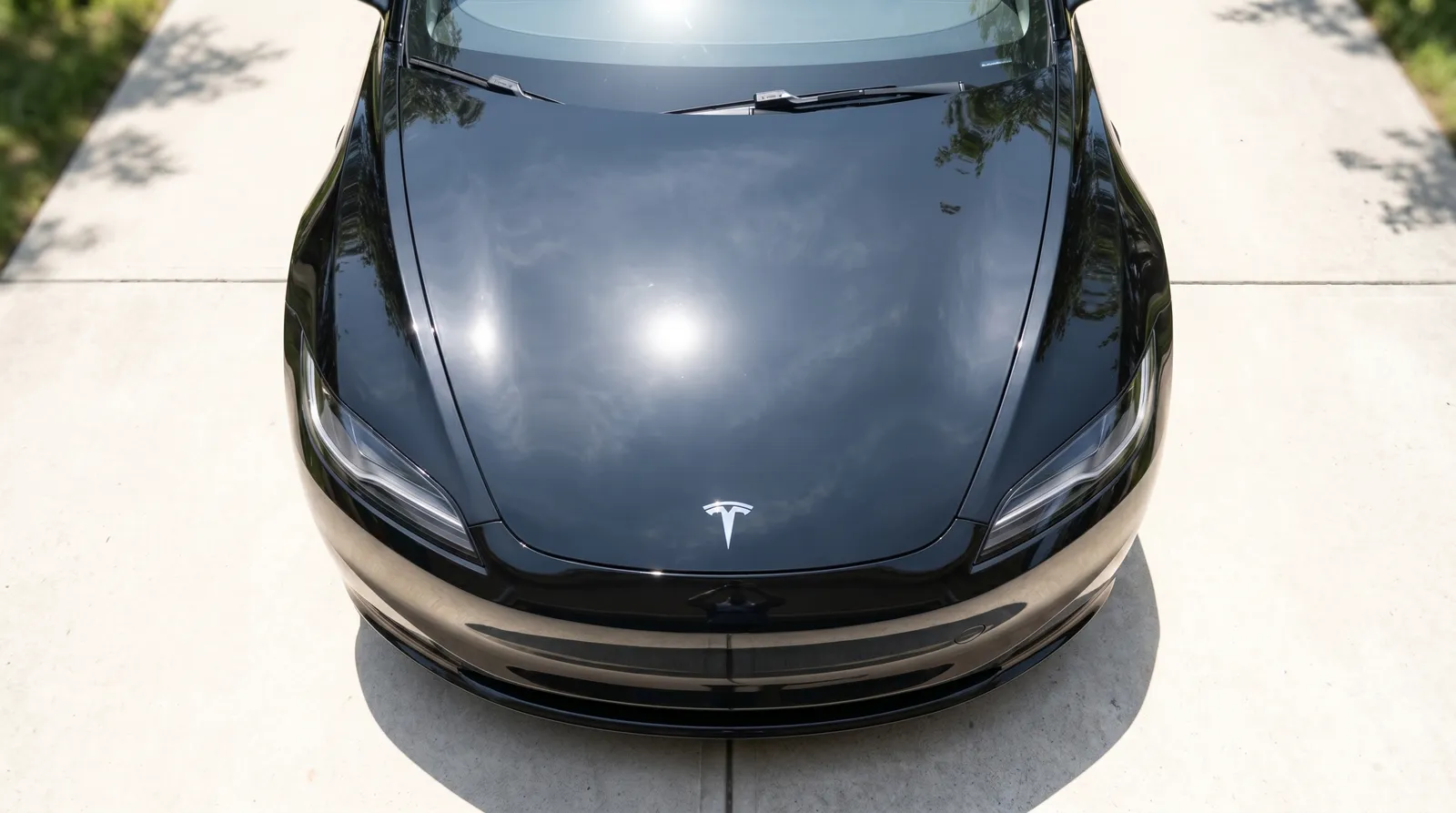 Black Tesla hood 2-step paint correction before and after — heavy swirl marks polished out — after