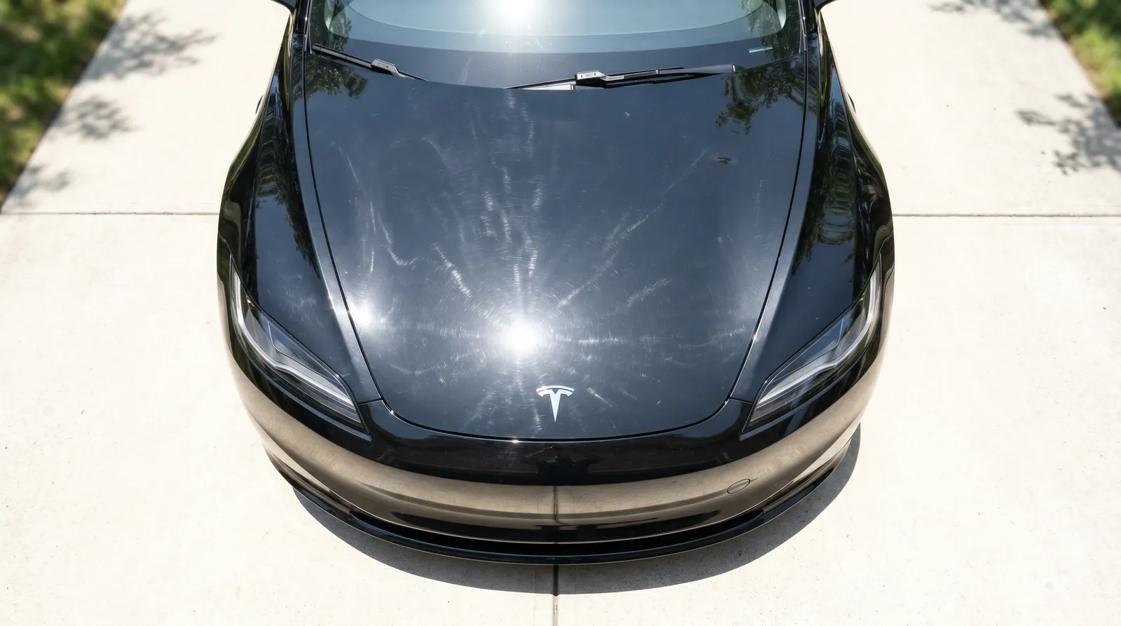 Black Tesla hood 2-step paint correction before and after — heavy swirl marks polished out — before